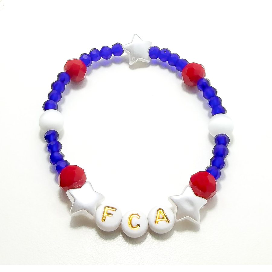 A blue, red, and white bracelet with star beads and gold letters spelling FCA